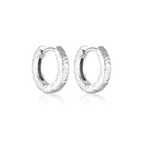 A pair of silver huggie textured earrings with a rhodium plated finish, hypoallergenic and nickel free.